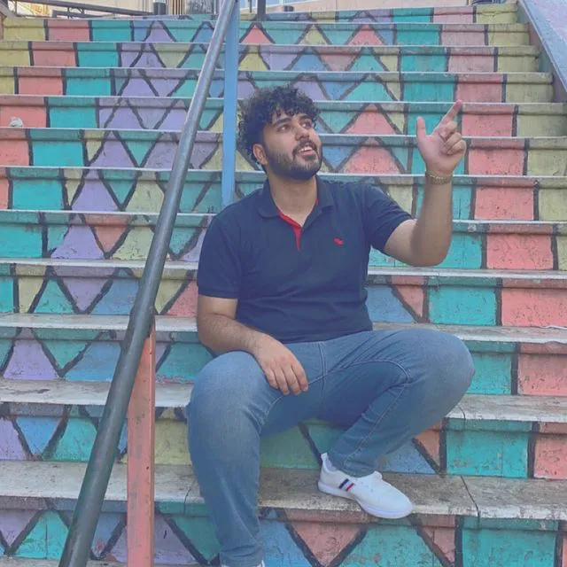 Nader Alzghoul sitting on a colourful staircase